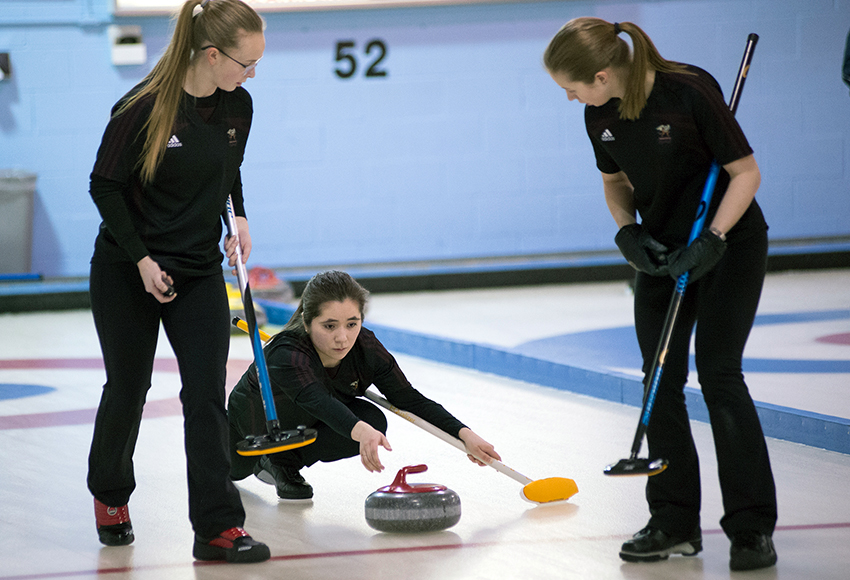 Hilary Charlie throws a rock while teammates Erin Wells, left and Andie Kurjata stand at the ready to sweep during action at the ACAC Winter Regional at Avonair Curling Club on Saturday (Len Joudrey photo).