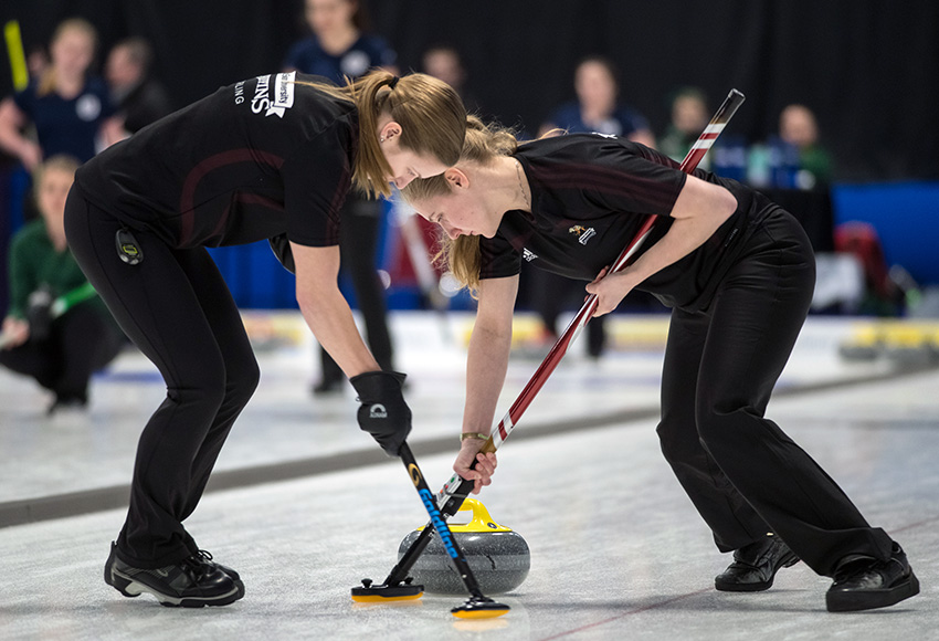 Andie Kurjata, left, and Taitan Hagglund sweep a rock during round robin action at the CCAA nationals (CCAA photo).
