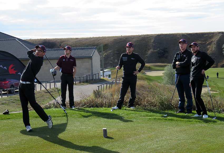 Members of the Griffins men's golf team watch a shot by Justin Berget during a practice round at the CCAA national championship last October in Medicine Hat (CCAA photo).