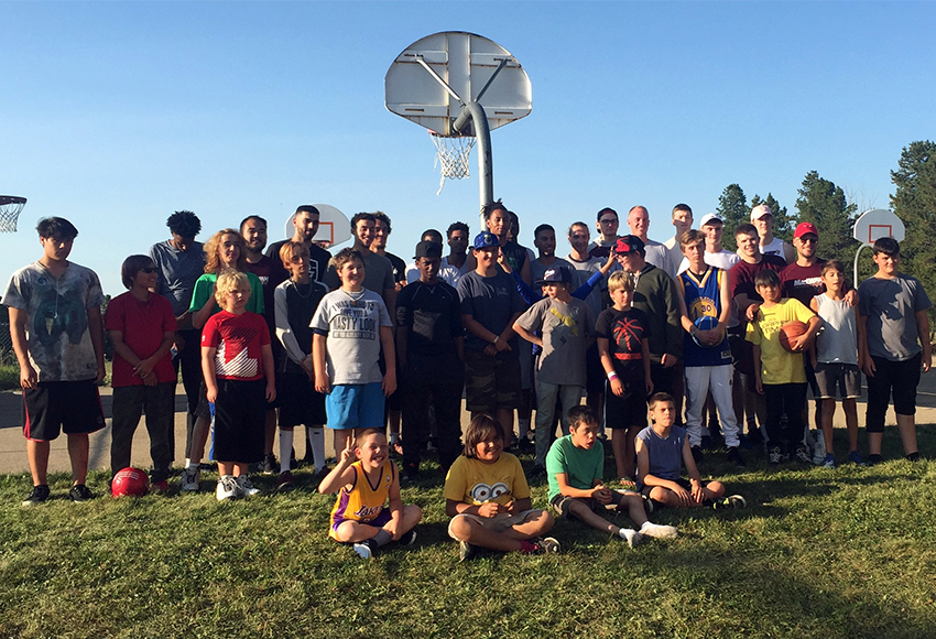 Members of the Griffins men's basketball team gather with kids from the Oak Hill Boys Ranch after repainting the basketball court.