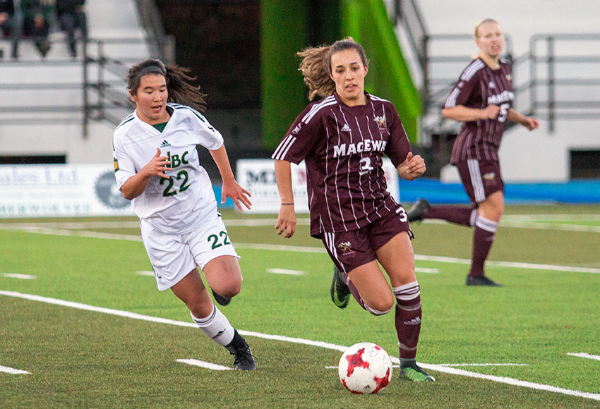 Brittany Costa carries the ball upfield against UNBC's Jenna Wild on Friday night (Rich Abney photo)