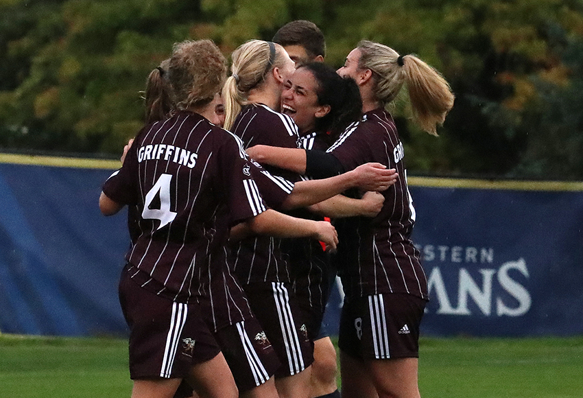 Griffins players surround Suekiana Choucair after she scored late in the first half on Friday. MacEwan tallied three times to stun Trinity Western 3-2 (Scott Stewart photo).