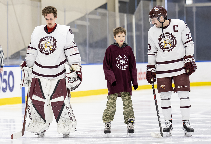'Skate with the Griffins' contest winner Wesley O’Greysik earned the right to skate out on the ice with the team before Saturday's Canada West contest as he lined up next to goalie Ashton Abel, left, and captain Kole Gable for the national anthem (Rebecca Chelmick photo).