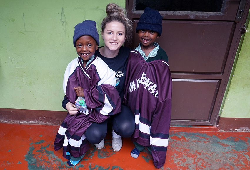 Kennedy Davidson poses with twins Daniel and Daudi, wearing Griffins jerseys, at the Hockey Hearts School & Dormitory in Tanzania last spring.