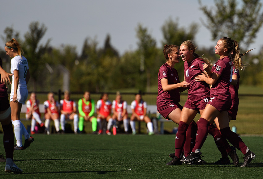 Raeghan McCarthy is mobbed by teammates after opening the scoring just 2:30 into Saturday's home opener. MacEwan defeated cross-town rival Alberta 2-0 (Chris Piggott photo).