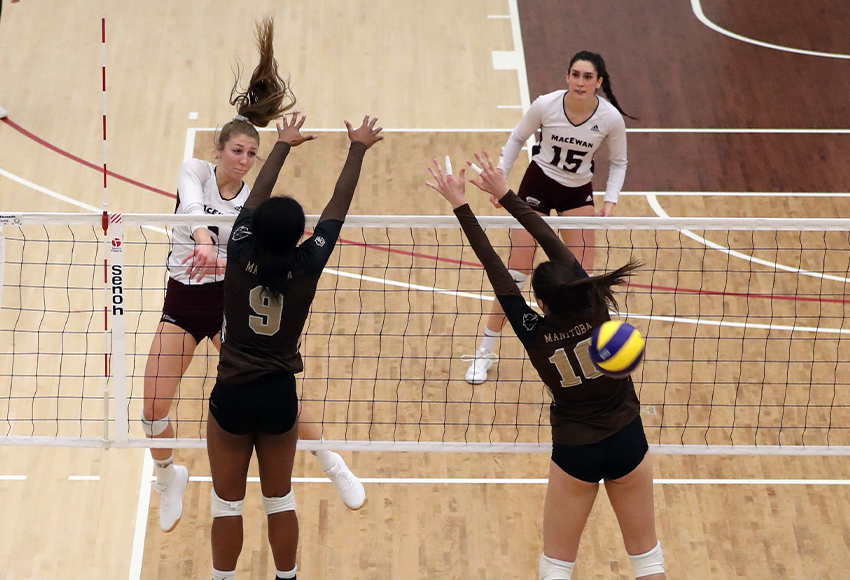 Haley Gilfillan blasts a kill through the Manitoba block with teammate Lauren Holmes in the background. Both players had 12 kills to lead MacEwan to a victory (Eduardo Perez photo).